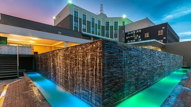 A modern building with a unique stone facade and a water feature in front. - Grand Aria Hotel (Gaborone)