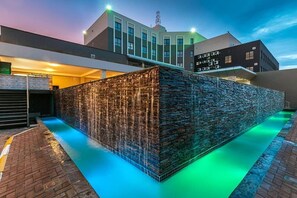 Un edificio moderno con una fachada de piedra singular y una fuente en la parte delantera.