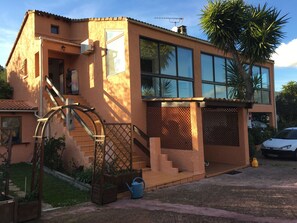 A two-story house with a large window, a water wheel, and a car parked in the driveway.