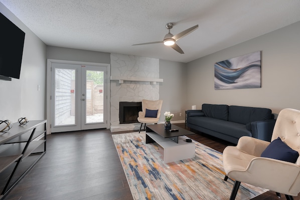 A modern living room with a fireplace, a sofa, a coffee table, and a ceiling fan.