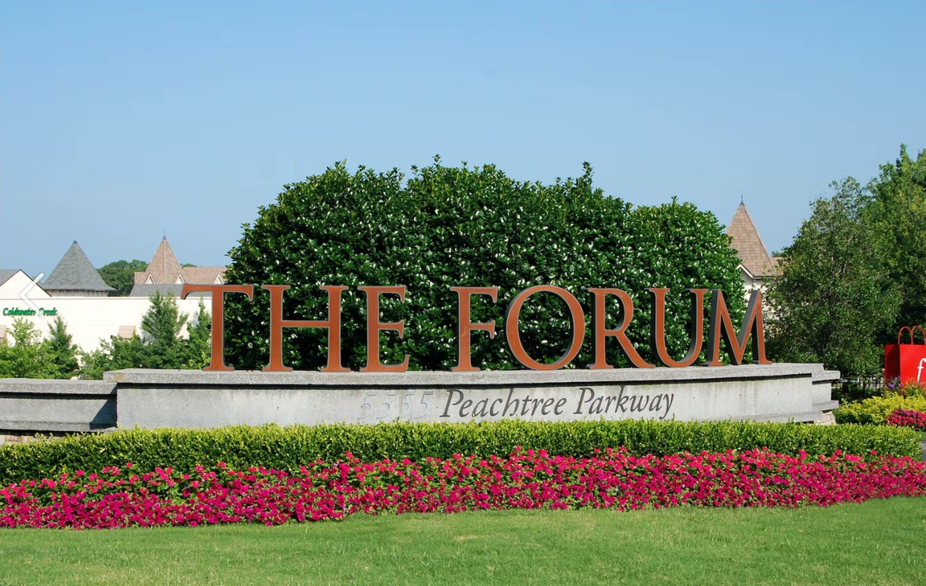 A sign with "THE FORUM" in large letters, Peachtree Parkway address, and a landscaped area with flowers.
