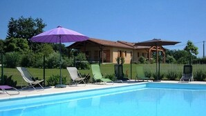 Une piscine avec des chaises longues et un parasol violet.
