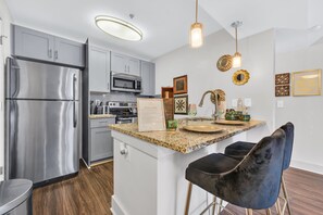 Eine moderne Küche mit Edelstahlgeräten, Granit Arbeitsplatten und einer zentralen Kochinsel mit Barhocker.