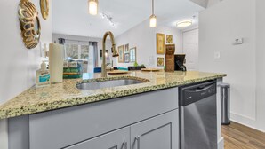 A modern kitchen with granite countertops, stainless steel appliances, and pendant lighting.