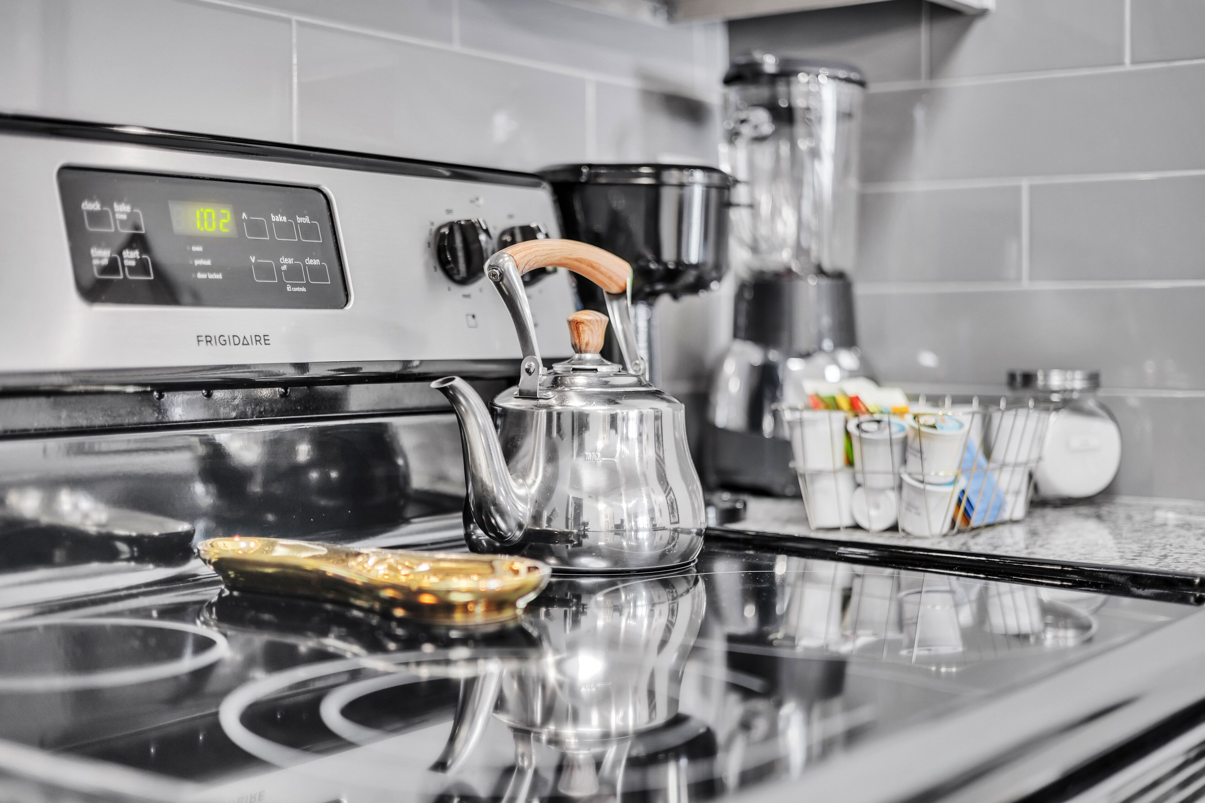 A kitchen with a stainless steel stove, a kettle, and a coffee maker.
