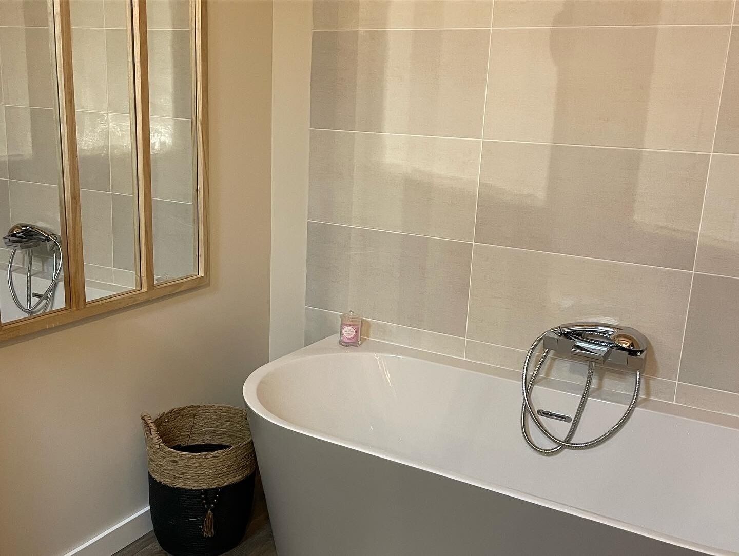 A bathroom with a freestanding bathtub, a mirror, and a trash bin.