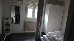 A bedroom with a bed, a wardrobe, a radiator, and a window with blinds. - APARTMENT GÎTE DE L'OBERHARTH COLMAR ALSACE (Colmar)
