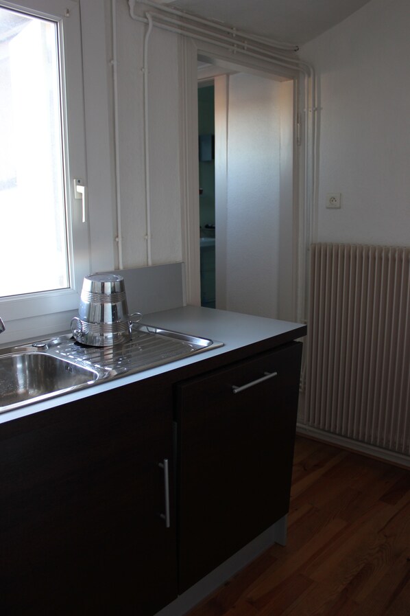 A kitchen with a stainless steel sink, a coffee maker, and a window.