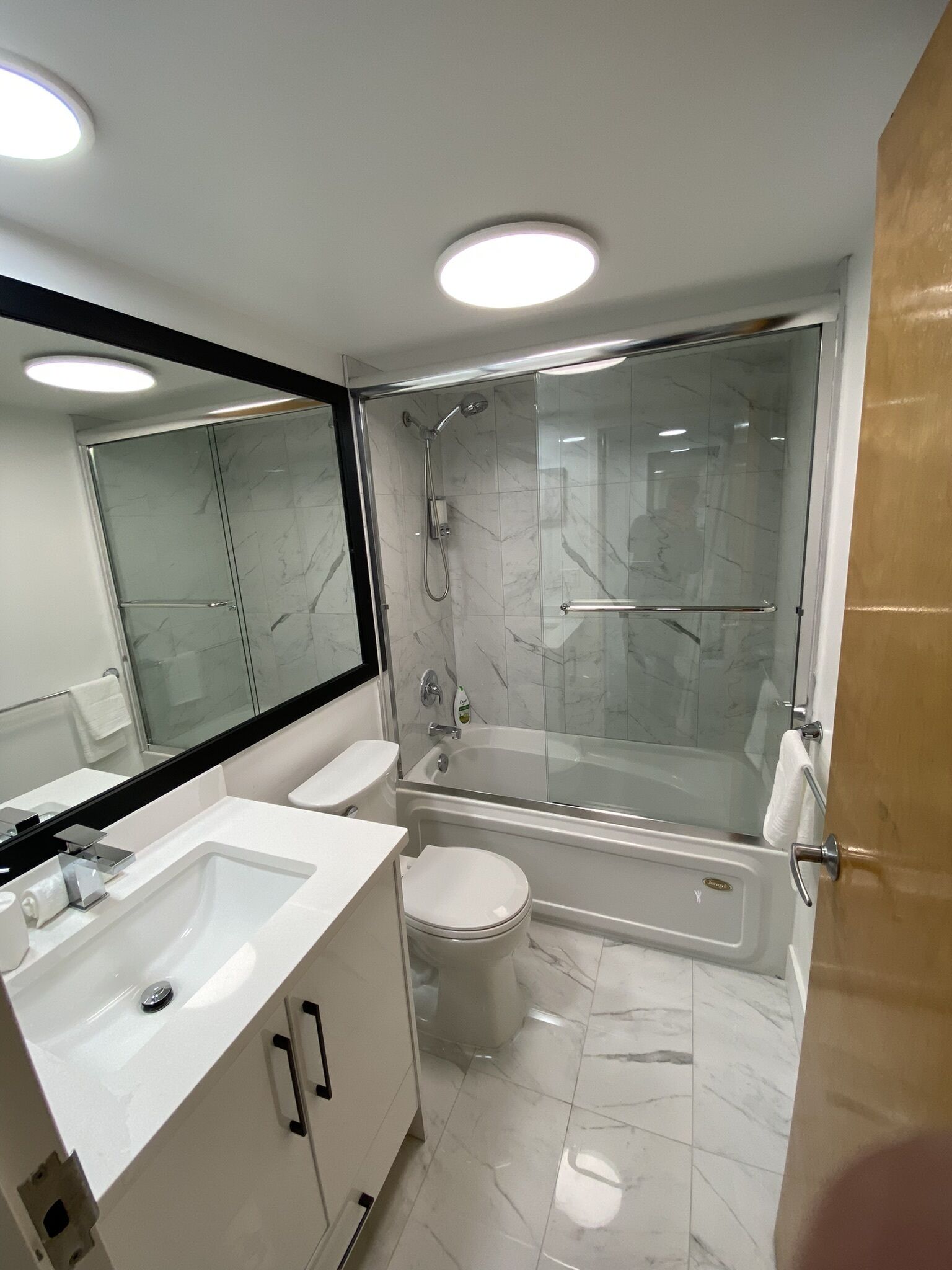 Une salle de bain moderne avec une douche à parois de verre, des toilettes blanches et un meuble-lavabo.