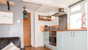 A kitchen with light blue cabinets, a wooden countertop, and a stainless steel range hood. - The Moonbeach Cabin (St Austell)