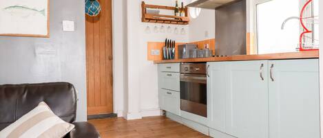 Una cocina con armarios azul claro, encimera de madera y campana extractora de acero inoxidable.