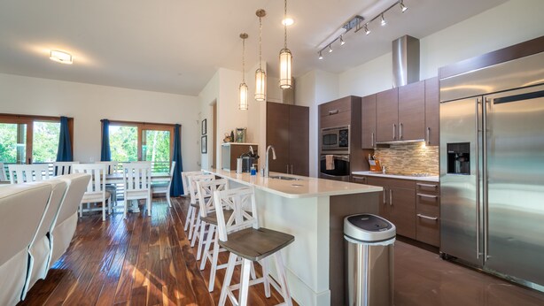 A modern kitchen with a central island, stainless steel appliances, and bar stools.