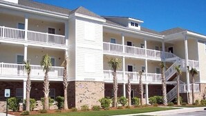 A multi-story hotel with balconies, a brick facade, and palm trees. - Beautiful 3 Bedroom Condo in Barefoot Landing (North Myrtle Beach)