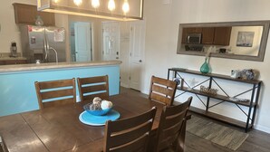 A dining area with a wooden table and chairs, a blue placemat, and a bowl of decorative items. - Beautiful 3 Bedroom Condo in Barefoot Landing (North Myrtle Beach)