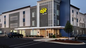 A modern hotel with a sign reading "apt suites" and a parking lot with cars.