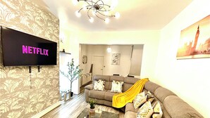 A living room with a flat-screen TV displaying 'NETFLIX', a sofa, a coffee table, and a chandelier. - Modern  -2 Bed Room House very Spacious  (Kingston upon Hull)