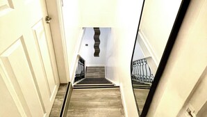 A staircase with wooden steps and a metal railing, leading to a landing with a chandelier. - Modern  -2 Bed Room House very Spacious  (Kingston upon Hull)