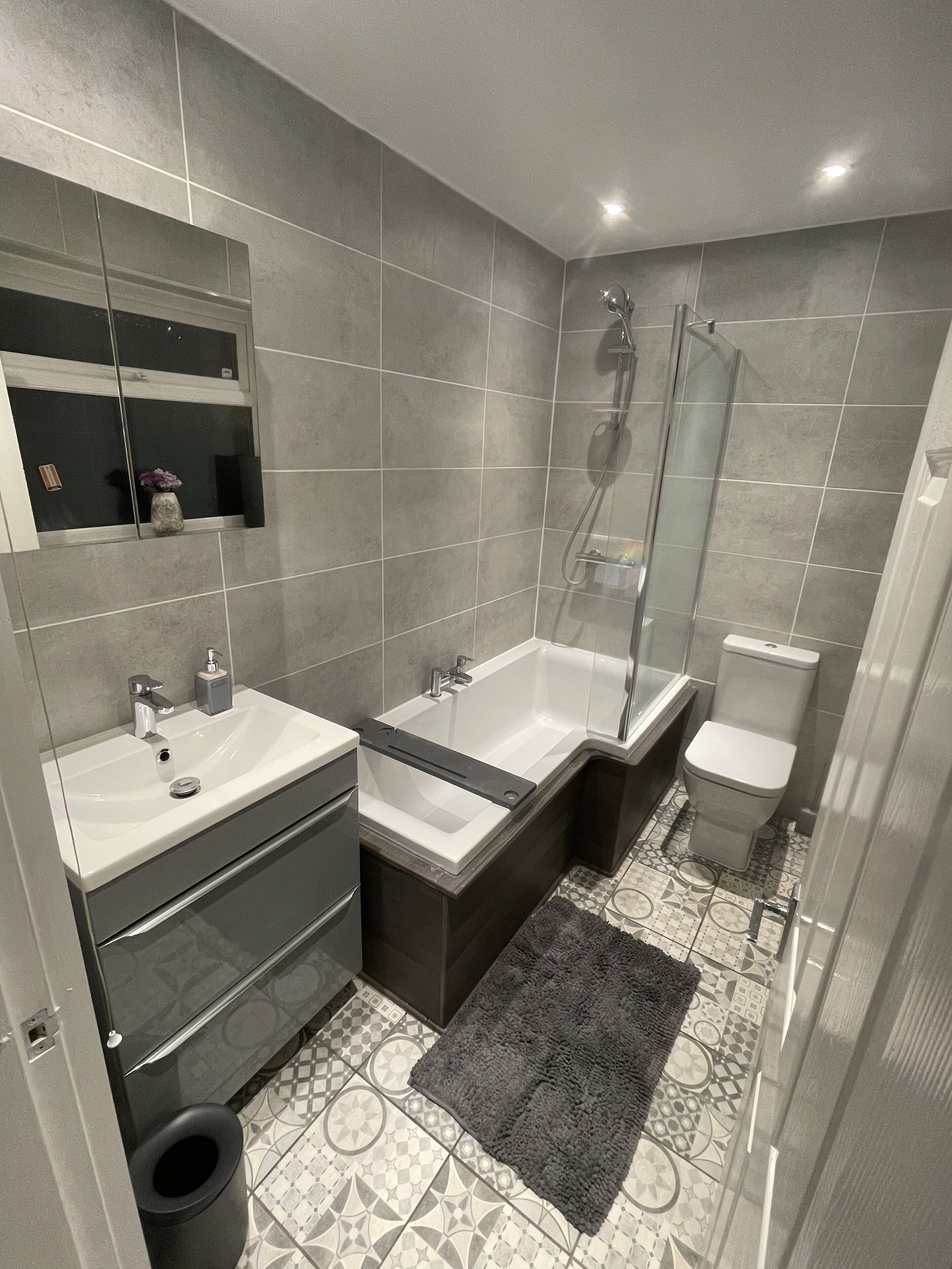 A modern bathroom with a double sink, a bathtub, a toilet, and a glass shower enclosure.