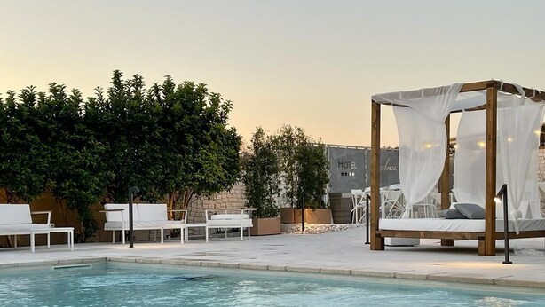 A pool area with lounge chairs and a canopy bed. - Hotel Posidonia (Porto Cesareo)