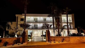 A two-story modern building with a balcony, palm trees, and a well-lit entrance. - Hotel Posidonia (Porto Cesareo)