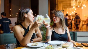 Two people toasting with drinks at a table with various dishes. - Catalina Hotel (San Pedro de Jujuy)