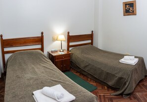 A twin room with two beds, a nightstand with a lamp, and a small wall decoration.