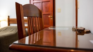A wooden dining table with a glass top, a chair, and a door in the background. - Catalina Hotel (San Pedro de Jujuy)
