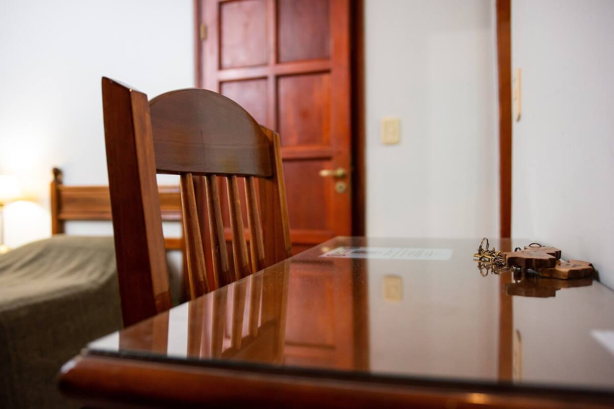 A wooden dining table with a glass top, a chair, and a door in the background.