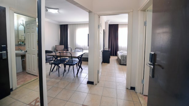 Ein Hotelzimmer mit Essbereich, einer Küchenzeile und einer Wohnfläche inklusive Sofa und Vorhängen.