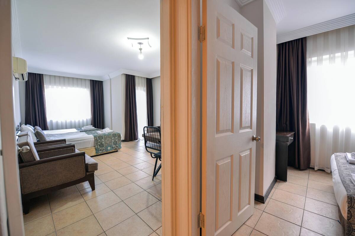 A hotel room with a bed, a sofa, a chair, and a small table.