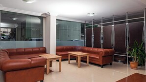 Eine Lobby mit Ledersofas, Holztischen und einer Topfpflanze.
