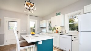 Une cuisine moderne avec des meubles blancs, un îlot de couleur turquoise et un bol de citrons posé sur le plan de travail.