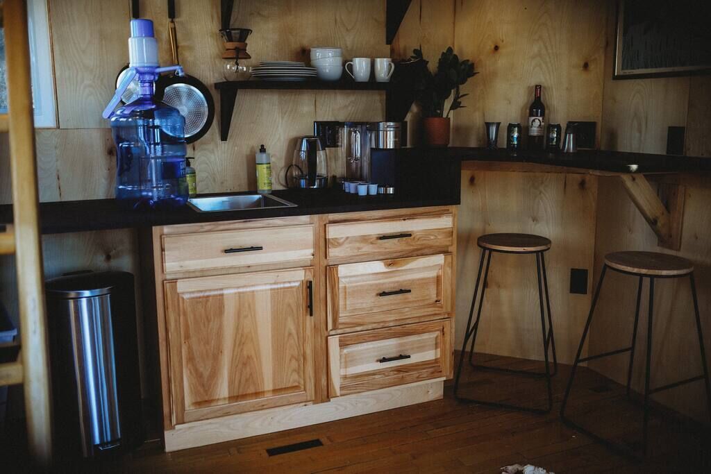 A kitchen with wooden cabinets, a sink, and bar stools.