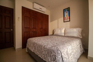 Une chambre à coucher avec un grand lit, une armoire en bois et un appareil de climatisation.