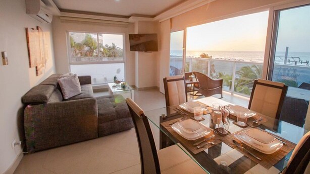A modern living room with a glass dining table set for four, a sofa, and a balcony with a view of the sea. - 2S3-2 APARTAMENTO EN CARTAGENA CON WIFI (Cartagena)