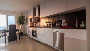 A modern kitchen with white cabinets, stainless steel appliances, and a dining area with a table and chairs. - 2S3-2 APARTAMENTO EN CARTAGENA CON WIFI (Cartagena)