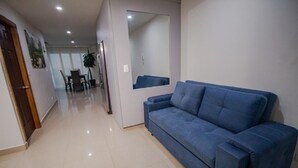 A modern living room with a blue sofa, a dining area with chairs and a table, and a hallway leading to another room. - 2S3-2 APARTAMENTO EN CARTAGENA CON WIFI (Cartagena)