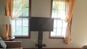Una sala de estar con televisión de pantalla plana, dos sofás, una mesa de centro y un tapete estampado.