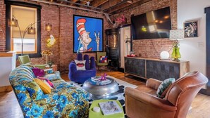 A modern living room with a large flat-screen TV, a blue armchair, a floral sofa, and a leather armchair. - Historic KC Firehouse  #8 - 40 (Kansas City)