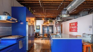 A modern kitchen with blue cabinets, a central island, and a vintage sign on the wall. - Historic KC Firehouse  #8 - 40 (Kansas City)