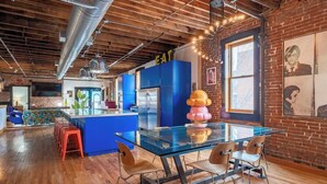 A modern kitchen with blue cabinets, a glass dining table, and a unique centerpiece. - Historic KC Firehouse  #8 - 40 (Kansas City)