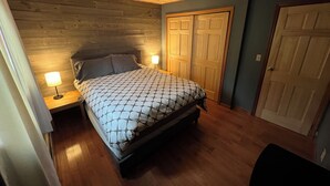 Une chambre avec un plafond en bois, un lit recouvert d’une couvre-lit à motifs, deux lampes de chevet et un ventilateur de plafond.