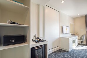 A hotel room with a minibar, a desk with a chair, a television, and a large mirror. - Eastin Hotel Vientiane Laos (Vientiane)
