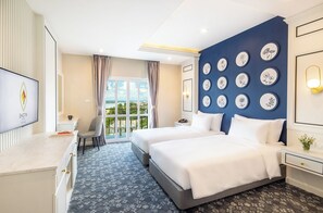 Habitación de hotel con cama, escritorio, silla, televisión y vistas al exterior.