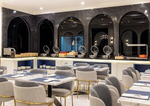 Un restaurant moderne avec des murs en marbre, plusieurs espaces de restauration et un comptoir de bar agrémenté d’objets décoratifs.