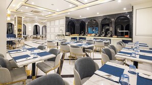 A modern dining area with tables set for multiple people, a bar area, and a kitchen visible in the background. - Eastin Hotel Vientiane Laos (Vientiane)