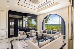 A spacious living area with a large arched window offering a view of the outdoors, a modern ceiling design, and a mix of seating arrangements. - Eastin Hotel Vientiane Laos (Vientiane)