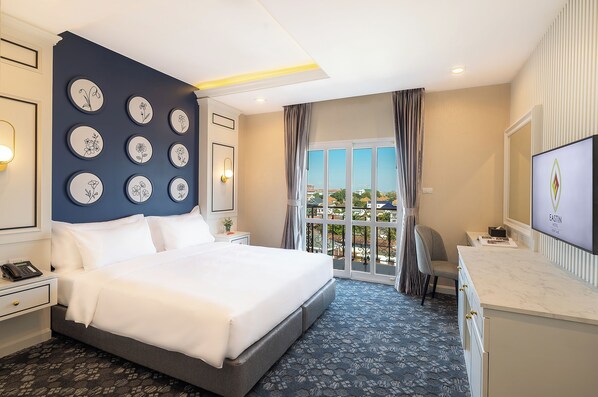 Una habitación de hotel con una cama grande, un escritorio, un televisor y vistas de la ciudad desde la ventana.
