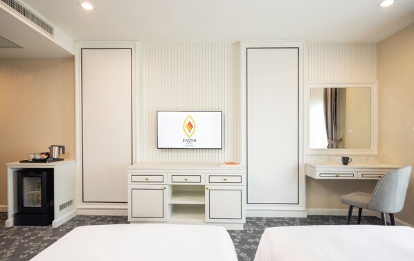 A hotel room with a bed, a desk, a vanity, and a framed logo on the wall. - Eastin Hotel Vientiane Laos (Vientiane)