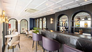 Un espace bar moderne avec des comptoirs en marbre, des tabourets de bar violets et une variété de bouteilles d’alcool.